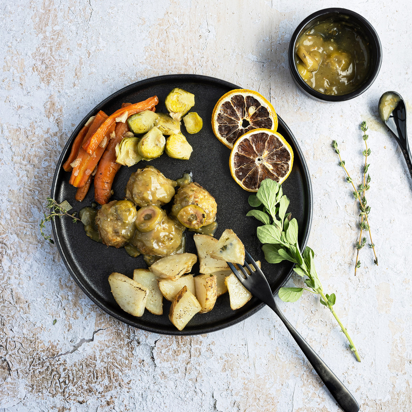 Une assiette de boulettes de dinde nappées d'une sauce citronnée accompagnées de choux de Bruxelles, de carottes et de pommes de terre. // A plate of turkey meatballs in a lemon sauce with Brussels sprouts, carrots and potatoes. 