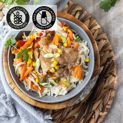 Dans un bol gris est déposé un lit de nouilles de riz, du poulet sauce thaï et des légumes variés. Un repas complet et coloré prêt en 5 minutes au micro-ondes. Un repas sans gluten et sans produits laitiers. // A gray bowl holds a bed of rice noodles, chicken in Thai sauce and a variety of vegetables. A complete, colorful meal ready in 5 minutes in the microwave. A gluten-free, dairy-free meal.