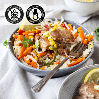 Dans un bol gris est déposé un lit de nouilles de riz, du poulet sauce thaï et des légumes variés. Un repas complet et coloré prêt en 5 minutes au micro-ondes. Un repas sans gluten et sans produits laitiers. // A gray bowl holds a bed of rice noodles, chicken in Thai sauce and a variety of vegetables. A complete, colorful meal ready in 5 minutes in the microwave. A gluten-free, dairy-free meal.