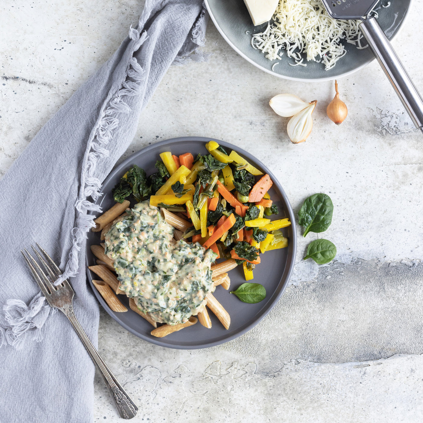 Photo d'un repas de pennes au saumon, nappées d'une sauce béchamel. Le tout servi avec une généreuse portion de légume colorés (carottes, épinards, carottes jaunes). // Photo of a meal of salmon penne, topped with a béchamel sauce. Served with a generous portion of colorful vegetables (carrots, spinach, yellow carrots). 