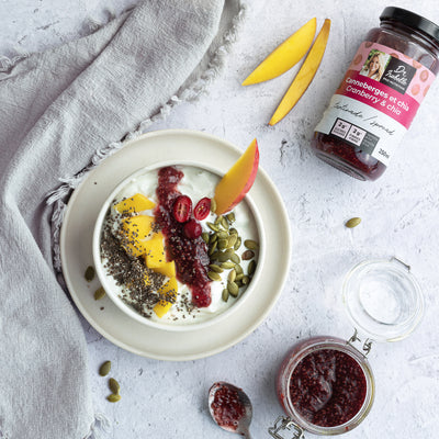 Photographie d'un mélange unique canneberges, et de graines de chia. Tartinade signée Isabelle Huot. Un gros bol rond rempli de yogourt et de fruits frais (mangue et canneberges) est situé au centre de l'image.  / Photography of a unique blend of cranberries and chia seeds. Spread by Isabelle Huot. A large round bowl filled with yogurt and fresh fruit (mango and cranberries) is at the center of the image.  