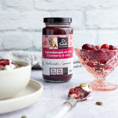 Photographie d'un mélange unique canneberges, et de graines de chia. Tartinade signée Isabelle Huot.  Un bol de canneberges fraîches est située à la droite du pot de tatinade. / Photography of a unique blend of cranberries and chia seeds. Spread by Isabelle Huot.  A bowl of fresh cranberries is located to the right of the jar of tatinade.